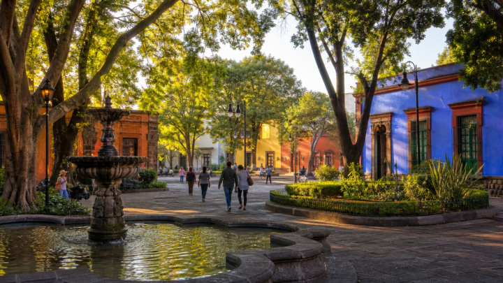 Plaza arbolada de Coyoacán con fuente y arquitectura histórica al amanecer